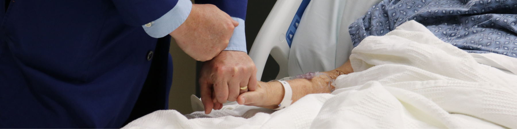 Chaplain holding the hand of a patient